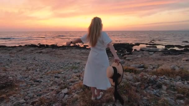 Mooie blonde vrouw in witte jurk reis naar Cyprus en geniet van de zomer zee zonsondergang in de buurt van het Lighthouse Beach. Freedom concept - Video