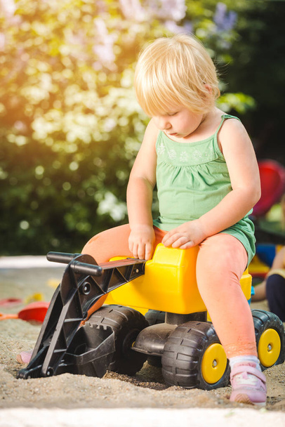 Niño cabalgando en un tractor de juguete en el patio de recreo
 - Foto, imagen
