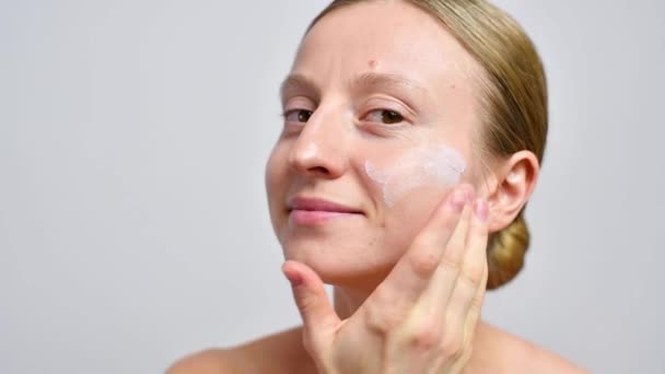 Skin care. Beautiful woman with healthy skin without makeup applying moisturizer on dry skin face - Imágenes, Vídeo