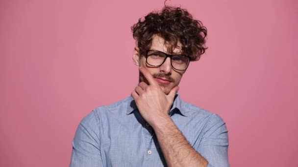 fiatal alkalmi férfi visel szemüveget álló és megható áll töprengő majd félrenéz rózsaszín stúdió háttér - Felvétel, videó