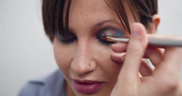 Glitter are applied to the womans eyelid, making of the evening makeup, eyes makeup, makeup artists work, close up makeup - Felvétel, videó