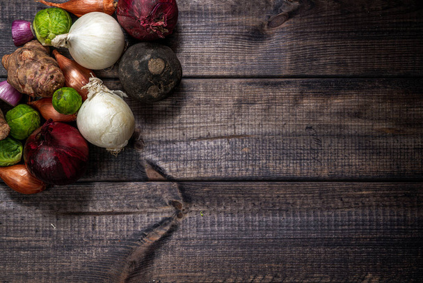 Conjunto de legumes em um fundo de madeira. Comer legumes e nutrição saudável. Cebolas, couves-de-bruxelas, chalotas, nabos e outros produtos hortícolas
. - Foto, Imagem
