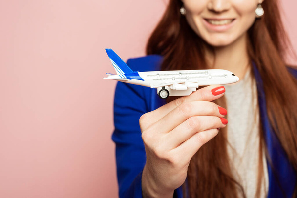Розбите зображення щасливої жінки з Європією, яка тримає модель літака, ізольовану на рожевому тлі. Закрий, копіювальний простір. - Фото, зображення