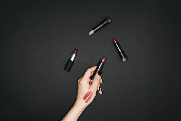 woman testing lipsticks on black background - Fotografie, Obrázek