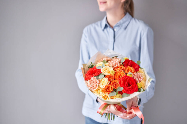 European floral shop. Beautiful bouquet of mixed flowers in woman hands. Work of the florist at a flower shop. Delivery fresh cut flower. - Foto, Imagem