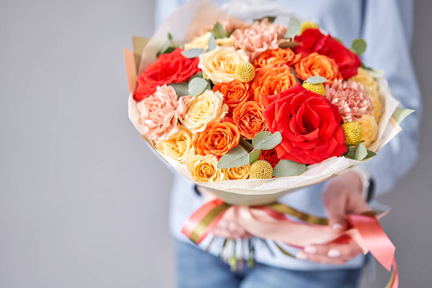 European floral shop. Beautiful bouquet of mixed flowers in woman hands. Work of the florist at a flower shop. Delivery fresh cut flower. - Fotó, kép