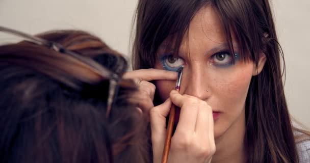 Portrait of brunette girl, makeup artist eyelashes of model eyes in makeup studio. Makeup and beauty - Filmati, video