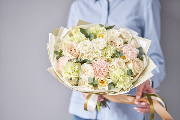 European floral shop. Beautiful bouquet of mixed flowers in woman hands. Work of the florist at a flower shop. Delivery fresh cut flower. - Foto, imagen