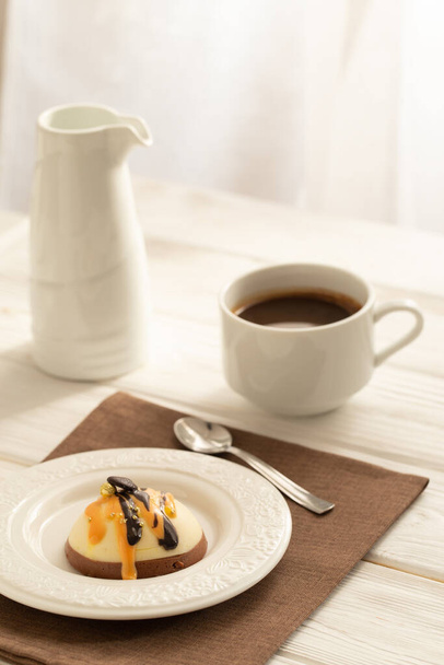 Still life with a cup of coffee and sweet cake on white wooden table. Breakfast in the morning sun - Foto, Imagen