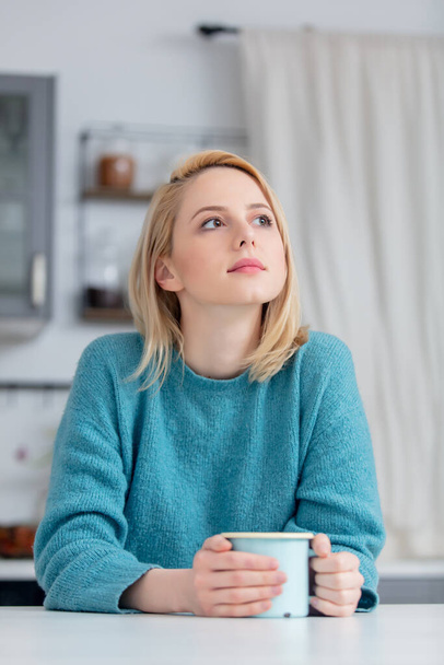 blonde lady with cup of coffee at kitchen  - Photo, Image