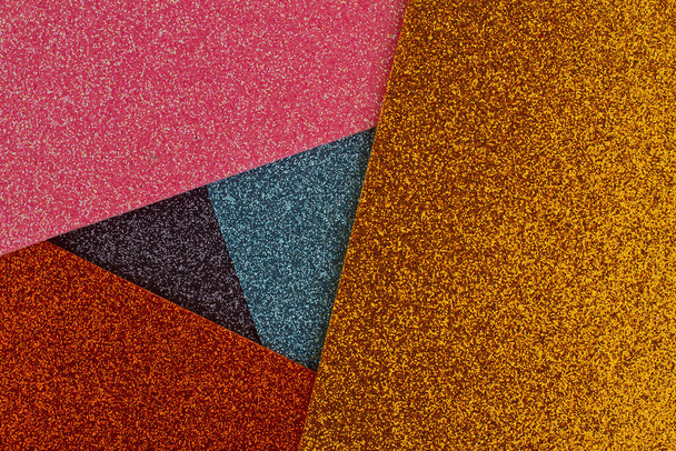 bovenste aanzicht close-up van abstracte geometrische driehoek achtergrond textuur met stralende glinsterende papieren stalen van verschillende kleuren - Foto, afbeelding