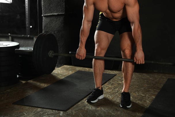 Man lifting barbell in modern gym, closeup - Foto, afbeelding