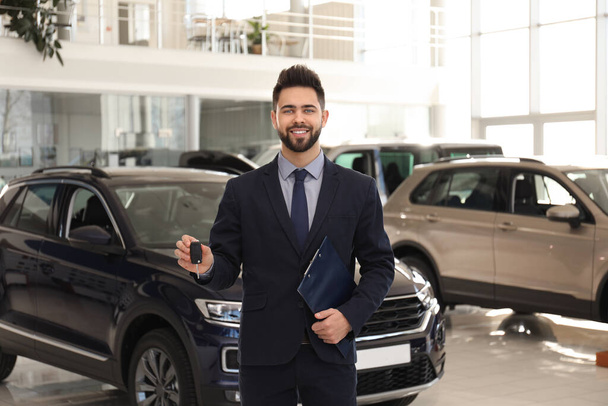 Salesman with key and clipboard in car salon - Photo, Image