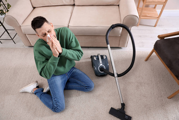 Man with vacuum cleaner suffering from dust allergy at home, above view - Valokuva, kuva