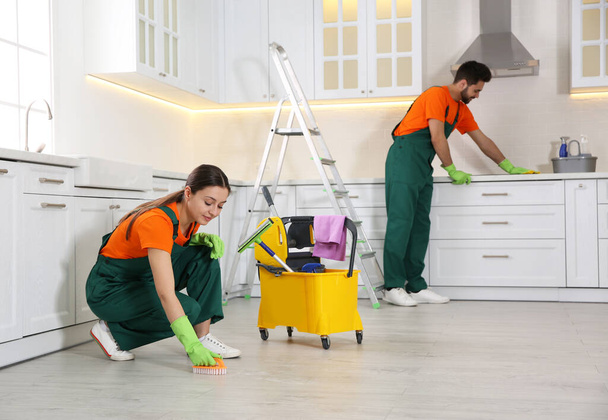 Team of professional janitors cleaning modern kitchen - Foto, Imagen
