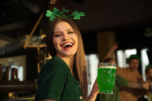 Young woman with glass of green beer in pub. St. Patrick's Day celebration - Φωτογραφία, εικόνα