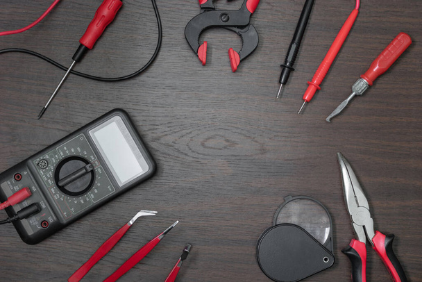 Red tool kit lies around on dark brown wooden table with space for text - Foto, afbeelding