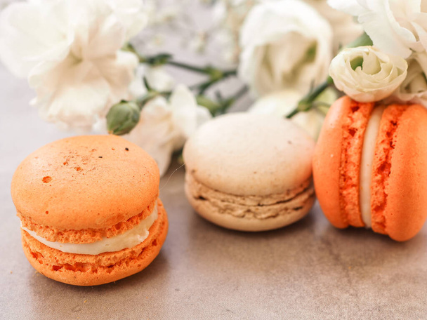 French macaroon cakes. Macaroons on a white plate with flowers on gray table background. Selective focus - Foto, Bild
