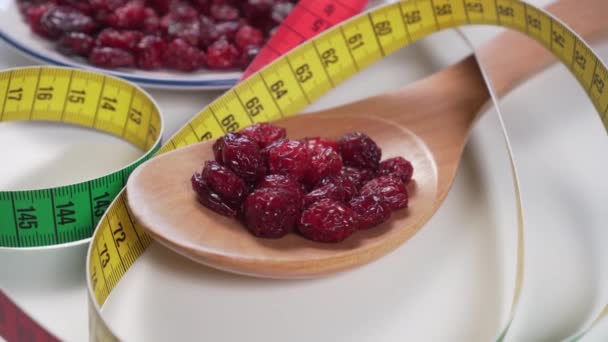 Red cranberries in a wooden spoon and in a white plate with a bright color centimeter on a light gray table. Berry diet. Slow motion Dolly macro shot - Filmagem, Vídeo