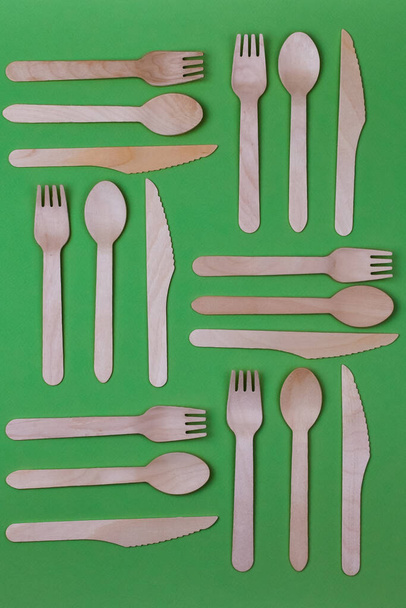 木製のスプーン、フォーク、緑の背景にナイフ。パターンだ。廃棄物ゼロコンセプト. - 写真・画像