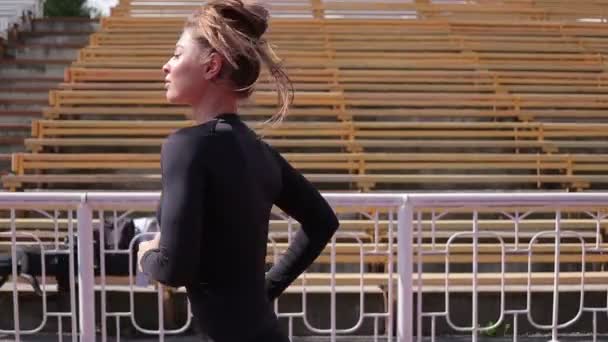 Karcsú nő fut a városi stadionban - Felvétel, videó