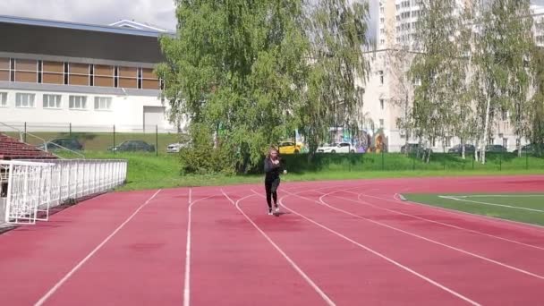Mujer sudorosa delgada corriendo en el campo de atletismo
 - Imágenes, Vídeo