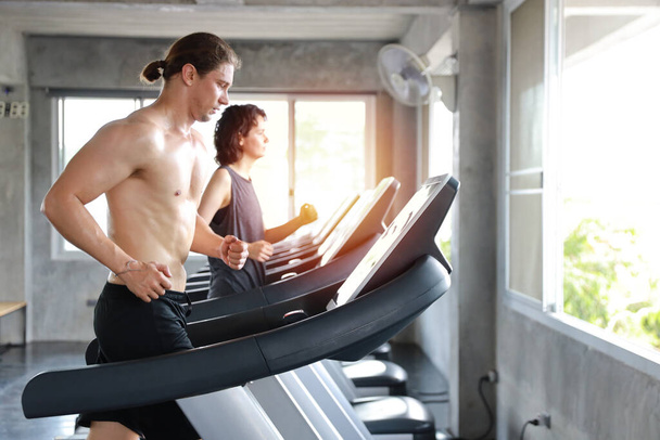 zblízka obraz zdravého a sexy bělocha svalovec v tričku, který běží na cvičebním stroji v tělocvičně  - Fotografie, Obrázek