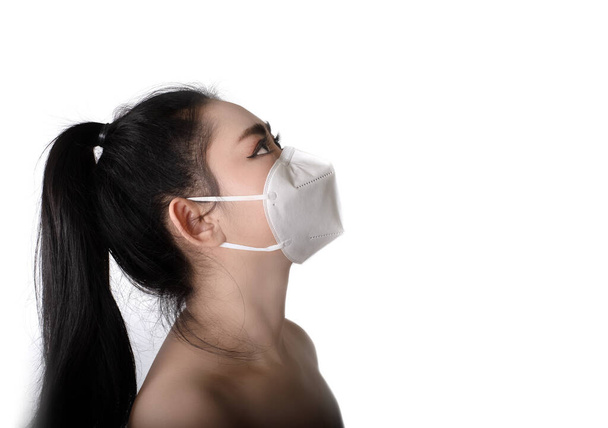 呼吸器の上に置く若いアジアの女性の側面図インフルエンザcovid-19コロナウイルスエボラPM2.5ほこりやスモッグ、安全ウイルス感染の概念として空中呼吸器疾患から保護するN95マスク - 写真・画像