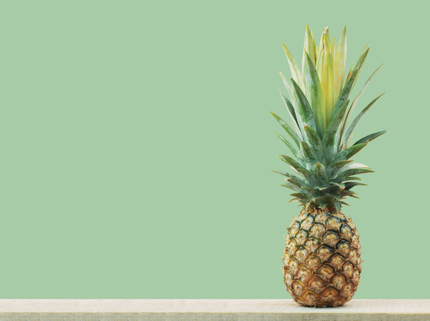 Ananas maturo su legno con lo sfondo verde
. - Foto, immagini