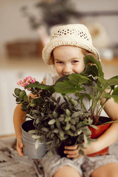 little girl with indoor flowers into pot - Foto, imagen