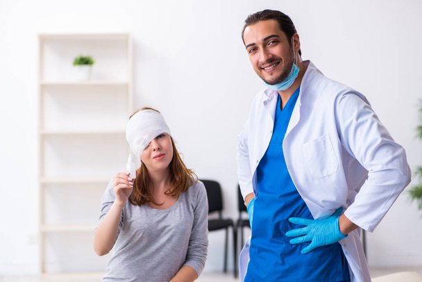 Joven cabeza lesionada mujer visitando joven médico masculino
 - Foto, Imagen