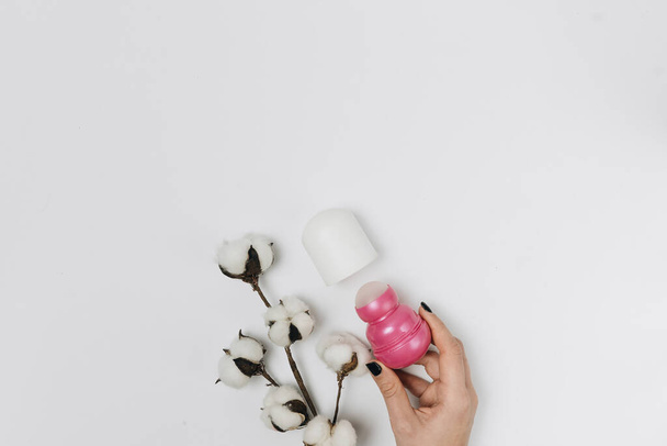 рука з дезодорантом з бавовняними квітами на білому тлі
 - Фото, зображення