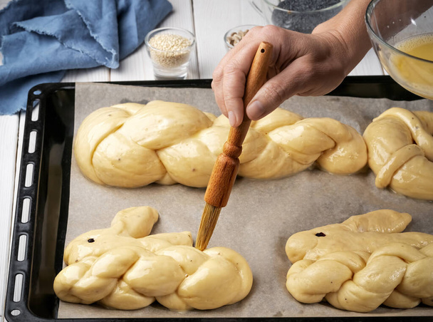 Easter pastries, challah, rabbit-shaped buns. Proofing baking before placing in the oven. Brush brush with butter buns before baking. Close-up. Braided sweet bread dough. - Фото, зображення
