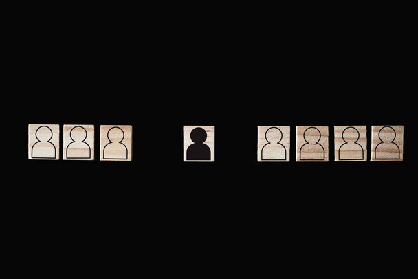 Pojęcie rasizmu i nieporozumień między ludźmi, uprzedzeń i dyskryminacji. Drewniany blok z białymi postaciami i jeden z czarnym mężczyzną - Zdjęcie, obraz