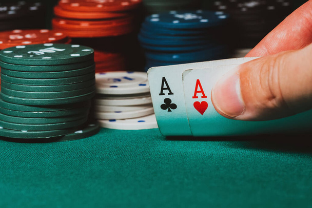 Spieler zeigt ein Paar Asse im Poker vor dem Hintergrund des Spiels Chips auf dem grünen Tisch - Foto, Bild