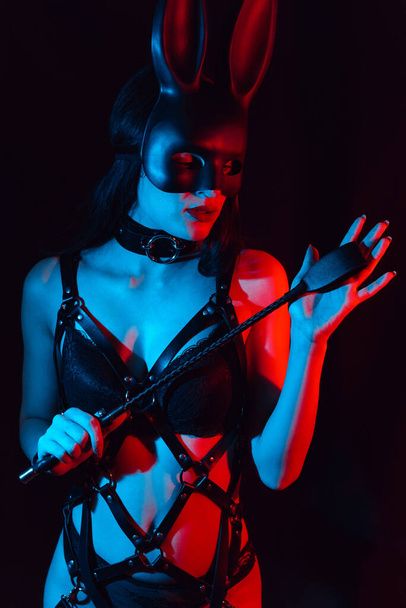 sexy girl mistress in leather harness and Bunny mask holds a Flogger whip - Φωτογραφία, εικόνα