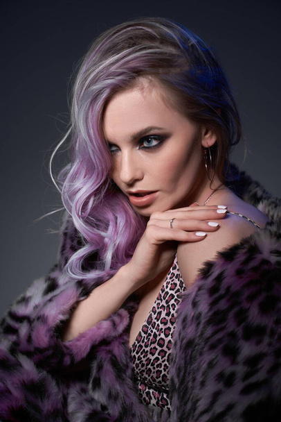 Blonde girl in leopard-print fur coat in studio - Фото, зображення
