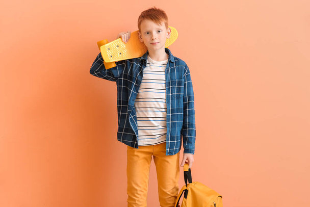 Cute little boy with skate and backpack on color background - Foto, Bild