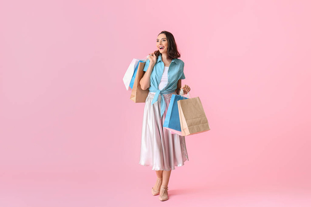 Beautiful young woman with shopping bags on color background - Photo, image