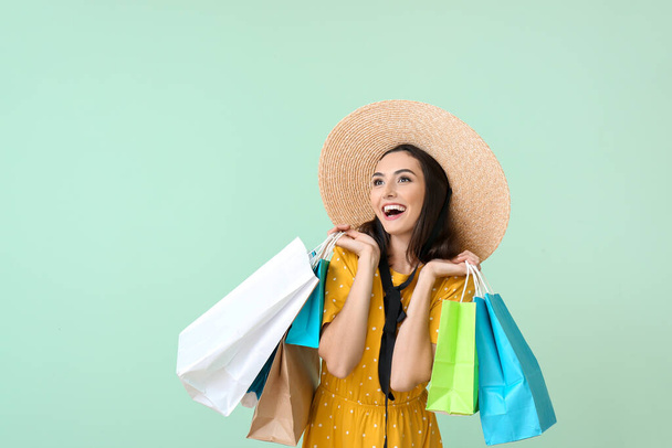 Όμορφη νεαρή γυναίκα με τσάντες ψώνια στο φόντο χρώμα - Φωτογραφία, εικόνα
