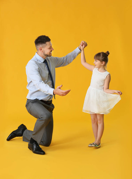 Isä ja hänen pieni tyttärensä tanssivat väritaustaa vasten
 - Valokuva, kuva