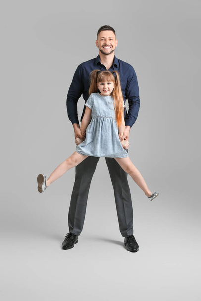 Apa és kislánya szürke háttér előtt táncolnak. - Fotó, kép