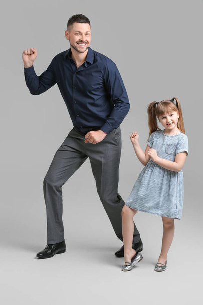 Father and his little daughter dancing against grey background - Photo, image
