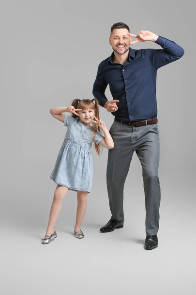 Father and his little daughter dancing against grey background - Foto, Imagem