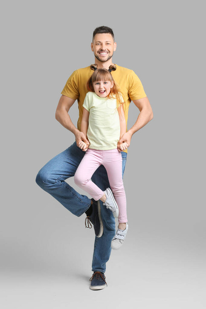 Isä ja hänen pieni tyttärensä tanssivat harmaalla taustalla
 - Valokuva, kuva