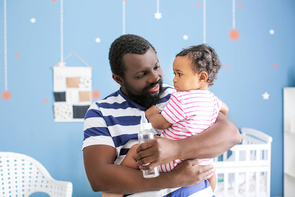 Hombre afroamericano con su lindo bebé en casa
 - Foto, Imagen