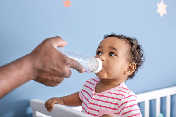 Afroamerikaner gibt seinem süßen Baby zu Hause Wasser - Foto, Bild