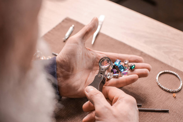 Juwelier onderzoekt edelstenen in werkplaats, close-up - Foto, afbeelding