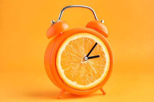 Creative alarm clock with citrus fruit on color background - Photo, Image