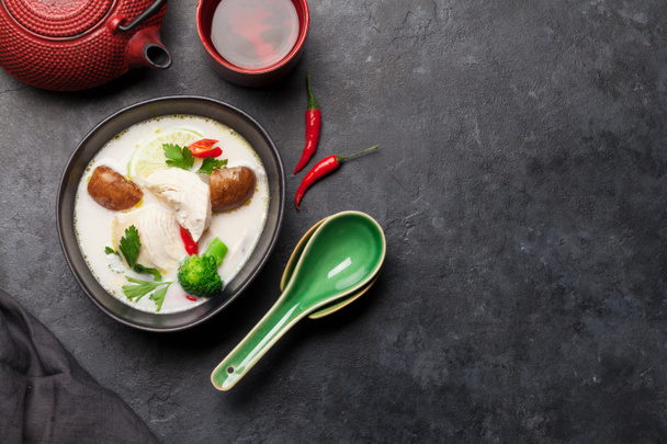 Soupe traditionnelle thaïlandaise Tom Kha avec poulet, champignons, lait de coco et épices chaudes. Avec théière verte et bol. Vue supérieure avec espace de copie
 - Photo, image
